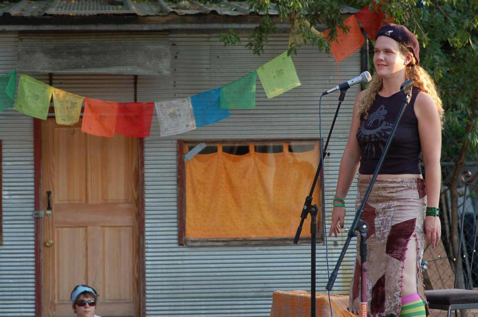 Melanie Rose Maxwell on an outdoor stage with a microphone