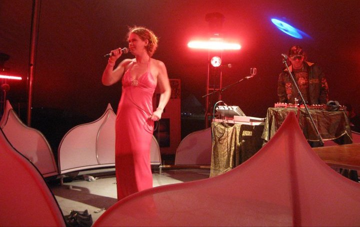Melanie Rose Maxwell performing under red stage lights